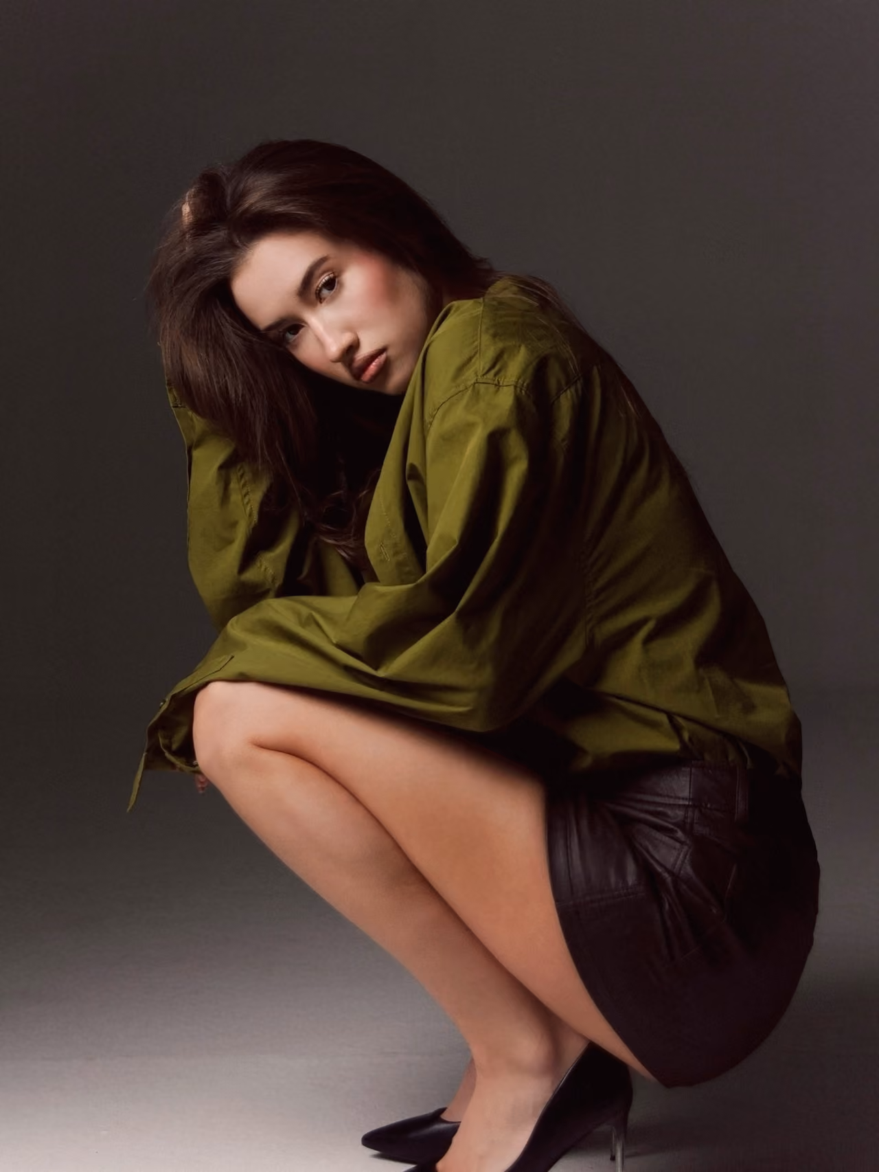 Woman in a green shirt crouching in the studio